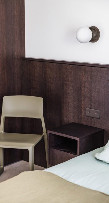 Tête de lit de la chambre en bois foncé. Idée pensée par le studio d'architecture d'intérieur Studio Naqaa.